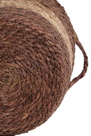 Nahaufnahme eines handgewebten Korbs aus Naturmaterialien mit seitlichem Griff, von unten betrachtet.