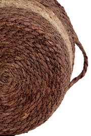 Nahaufnahme eines handgewebten Korbs aus Naturmaterialien mit seitlichem Griff, von unten betrachtet.