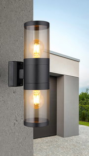 Moderne Außenleuchte mit zylindrischem Design, an einer Wand montiert, mit warmem Lichtschein, seitliche Perspektive.