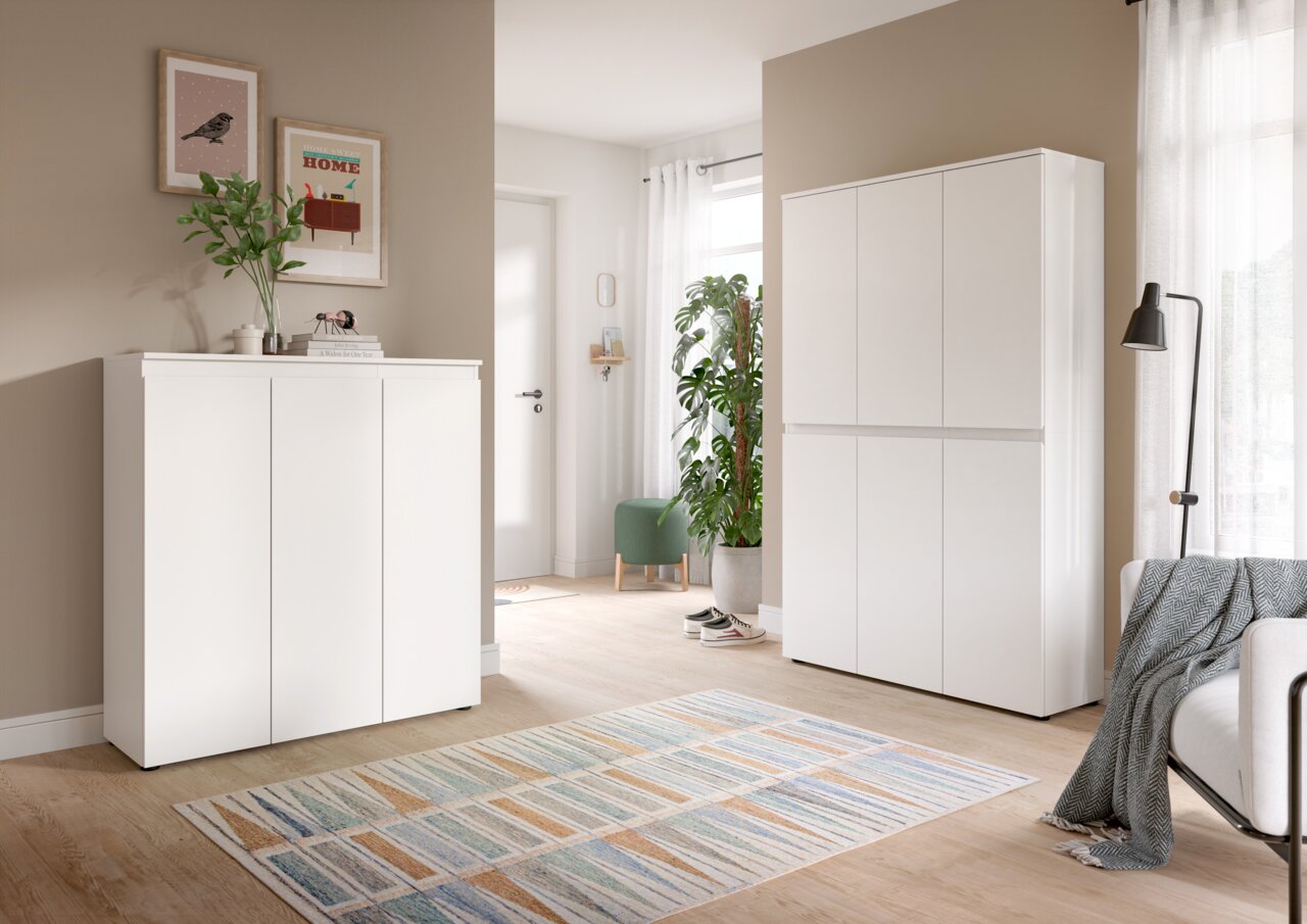 MID.YOU Universalschrank Set SCARPA Heller Wohnraum mit zwei weißen Schränken: links ein niedriges Sideboard mit drei Türen, rechts ein hoher Schrank mit sechs Türen, beide in Frontansicht aus leicht schräger Perspektive.