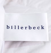Nahaufnahme eines Etiketts der Billerbeck Daunendecke POLARSTERN, auf einer weißen Oberfläche liegend.