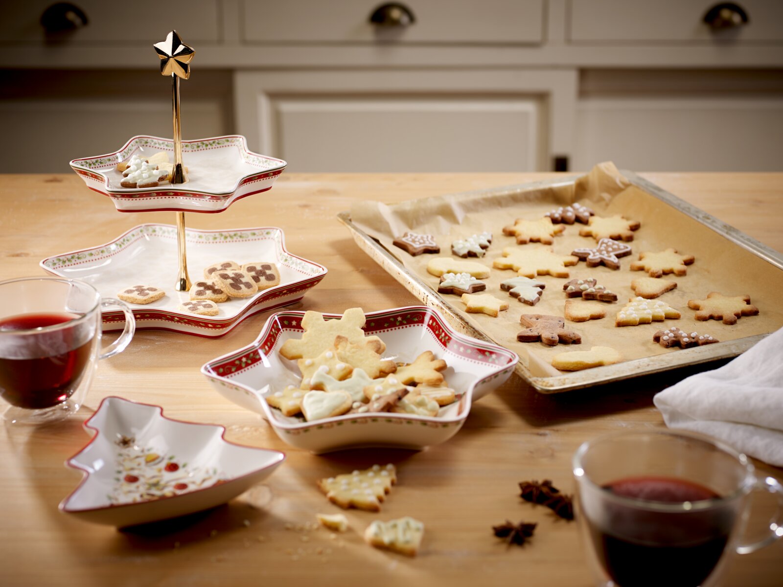 Weihnachtliche Stern-Etagere und sternförmige Servierschalen mit rot-grünem Dekor, gefüllt mit Plätzchen, aus leicht erhöhter frontaler Perspektive arrangiert.