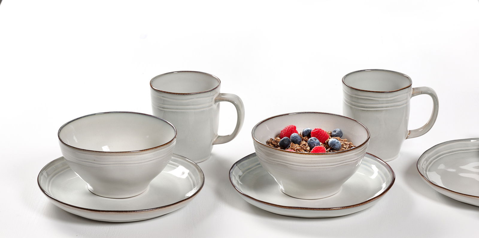 Frontalansicht eines 12-teiligen Frühstückssets mit Tassen, Schalen und Tellern in schlichtem Design.