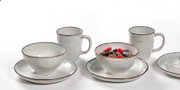 Frontalansicht eines 12-teiligen Frühstückssets mit Tassen, Schalen und Tellern in schlichtem Design.