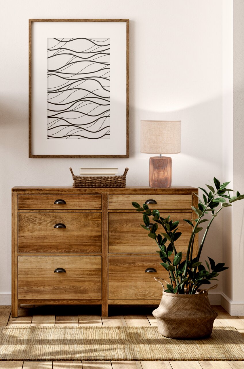 Tischleuchte Malik mit rechteckigem Holzfuß und beigem Stoffschirm, auf einer Holzkommode stehend, seitliche Perspektive.