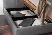 Polsterbett mit Stauraum, seitliche Perspektive, geöffnet mit Kissen und Decken.