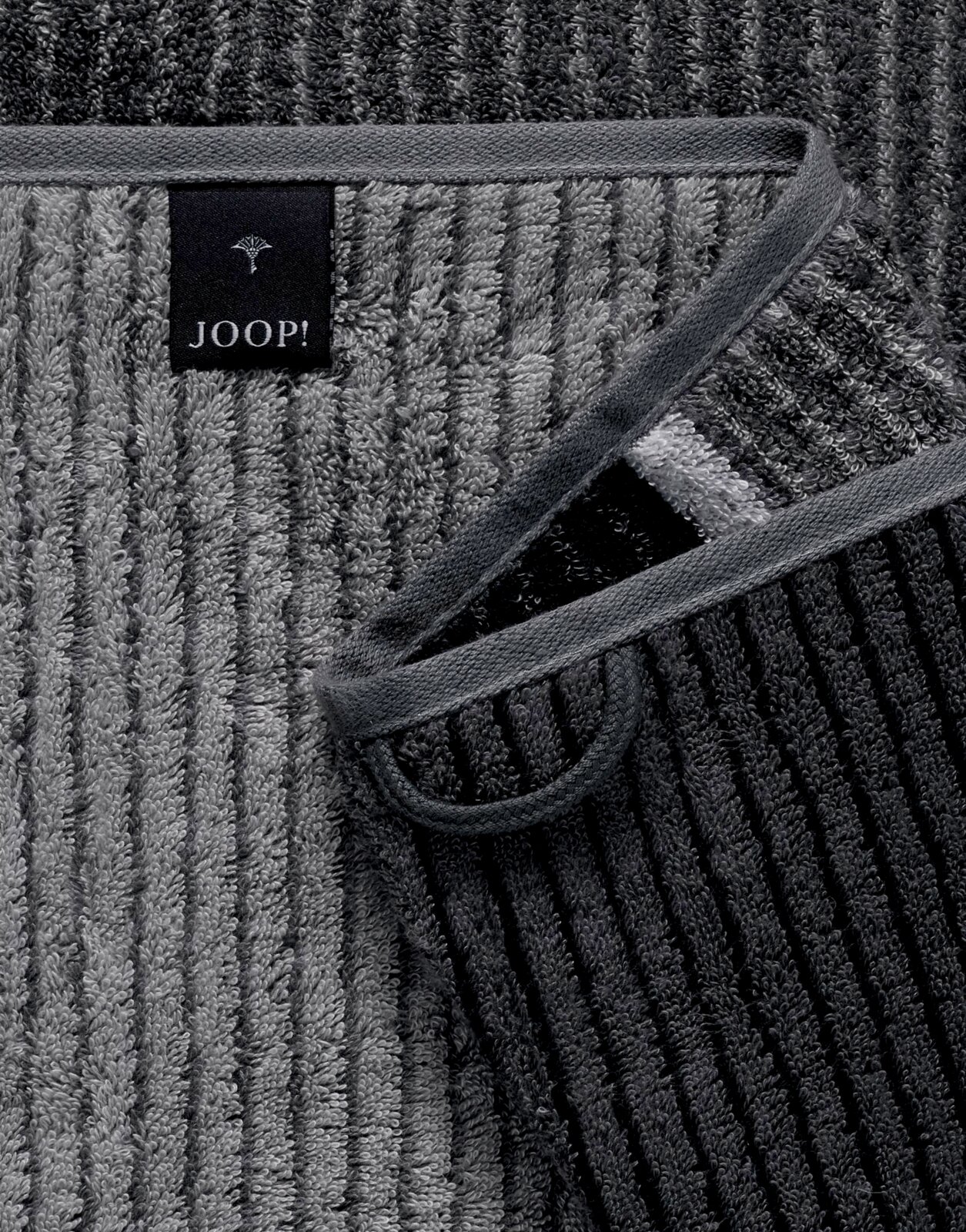 Grijze douchehanddoek met fijne strepen en merklabel, close-up