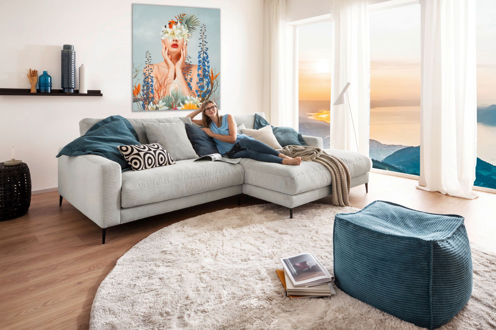 Gemütliche Longchairkombination in einem modernen Wohnzimmer mit Blick auf den Sonnenuntergang durch große Fenster. Eine Person entspannt sich auf dem Sofa, umgeben von stilvollen Kissen und einem Kunstwerk an der Wand. Perspektive: Frontalansicht.