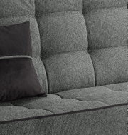 Nahaufnahme eines grauen Schlafsofas mit schwarzem Kissen, seitliche Perspektive