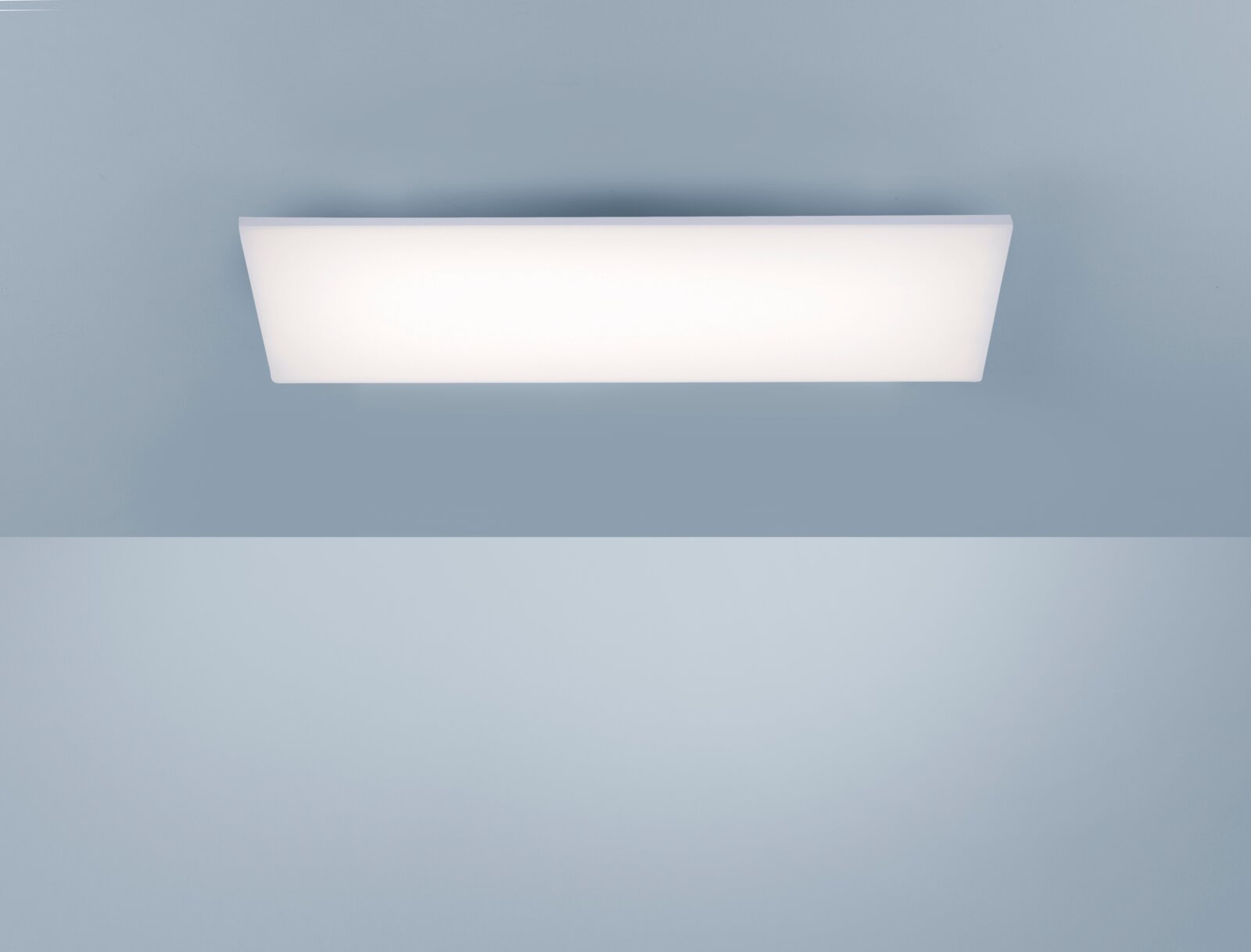 Rechteckige, flache LED-Deckenleuchte mit weißer Diffusorfläche an einer hellblauen Decke, frontal von unten aufgenommen.