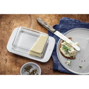 Butterdose LOFT aus Glas und Metall, von oben fotografiert, mit einem Stück Butter auf einem Holztisch neben einem Teller mit Brot und Käse.