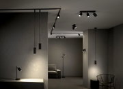 Moderne schwarze LED-Spot- und Pendelleuchten an Decke und Schienen im minimalistischen Wohnraum, perspektivisch aus leichtem Untersichtwinkel nach oben aufgenommen