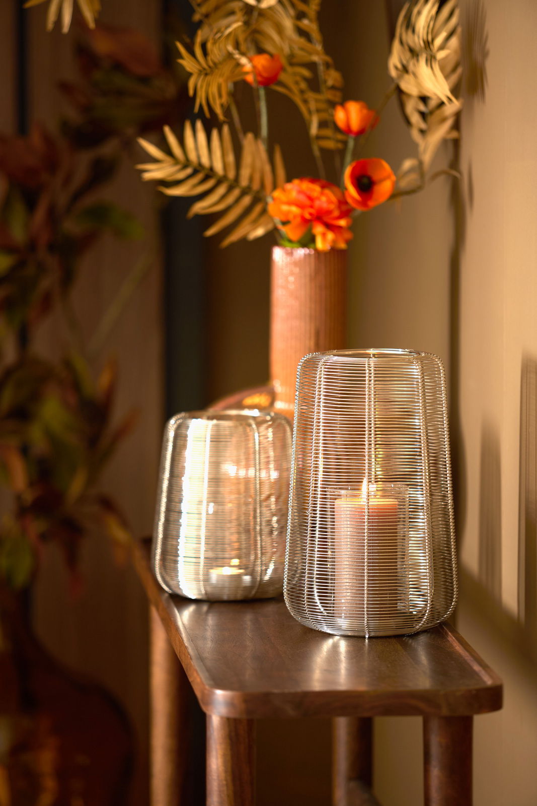 Light&Living Windlicht ADETA Windlicht aus Metallgeflecht mit brennender Kerze, auf einem Holztisch stehend, im Hintergrund eine Vase mit orangefarbenen Blumen, seitliche Perspektive