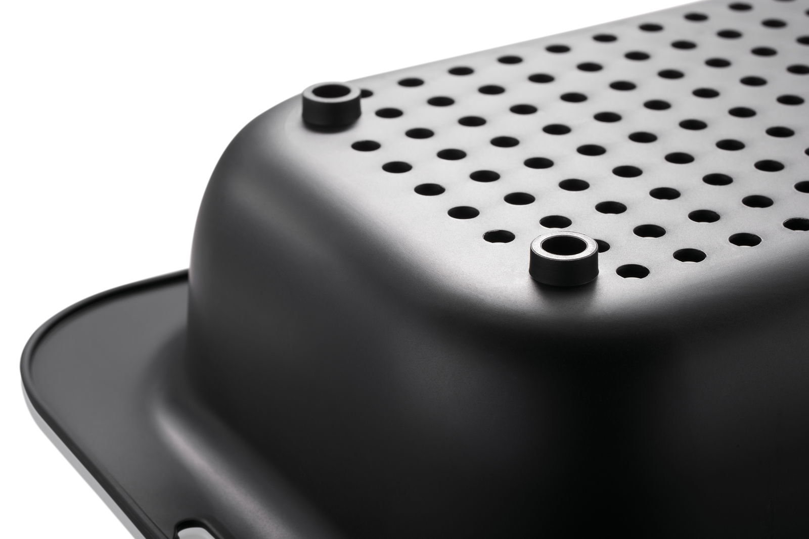 Nahaufnahme eines schwarzen Spülbeckensiebs mit runden Löchern und erhobenen Füßen, seitliche Perspektive