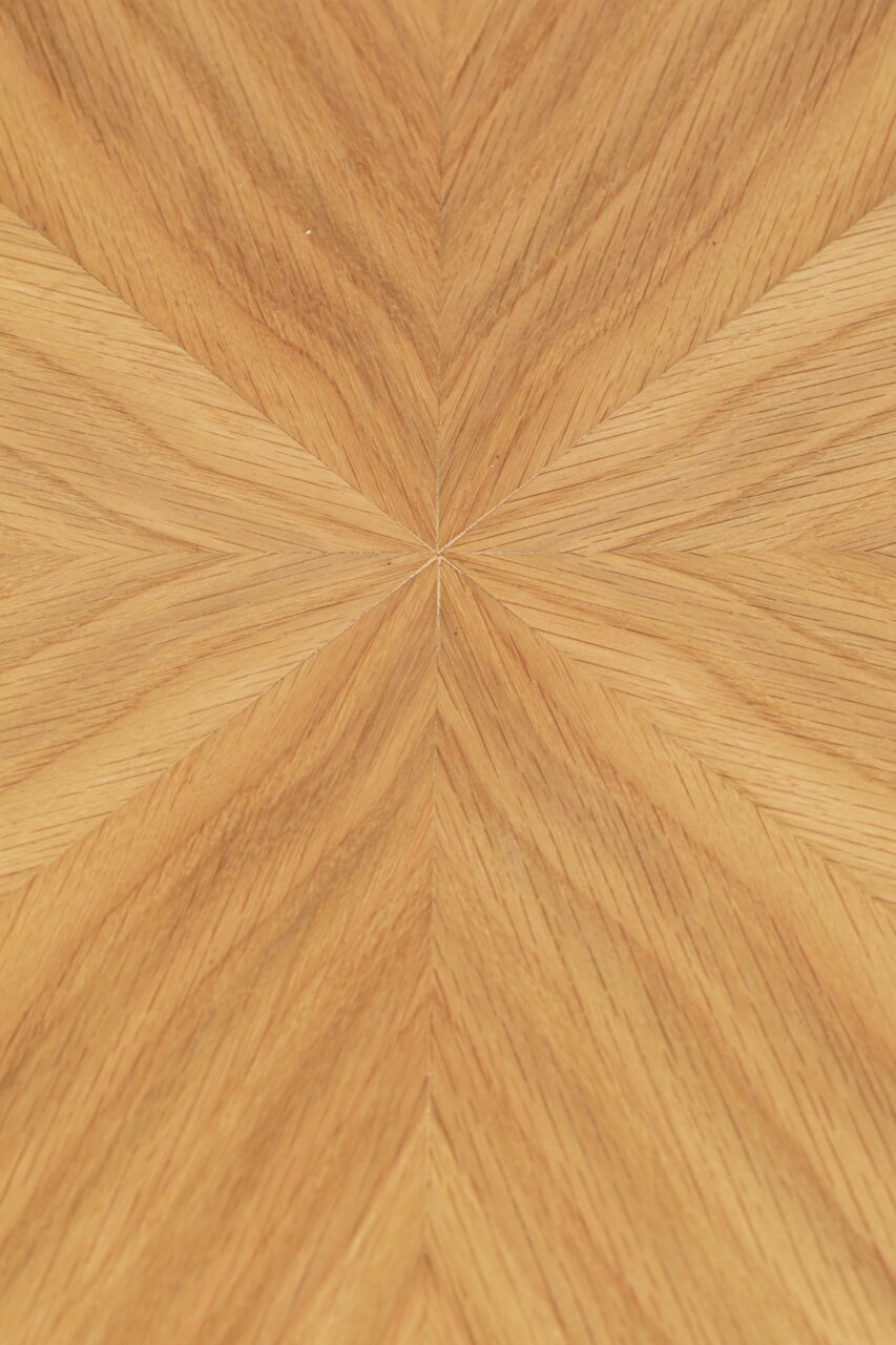 Nahaufnahme der Tischplatte eines Esstisches mit einem geometrischen Holzfurniermuster in warmen Holztönen, von oben betrachtet.