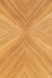 Nahaufnahme der Tischplatte eines Esstisches mit einem geometrischen Holzfurniermuster in warmen Holztönen, von oben betrachtet.