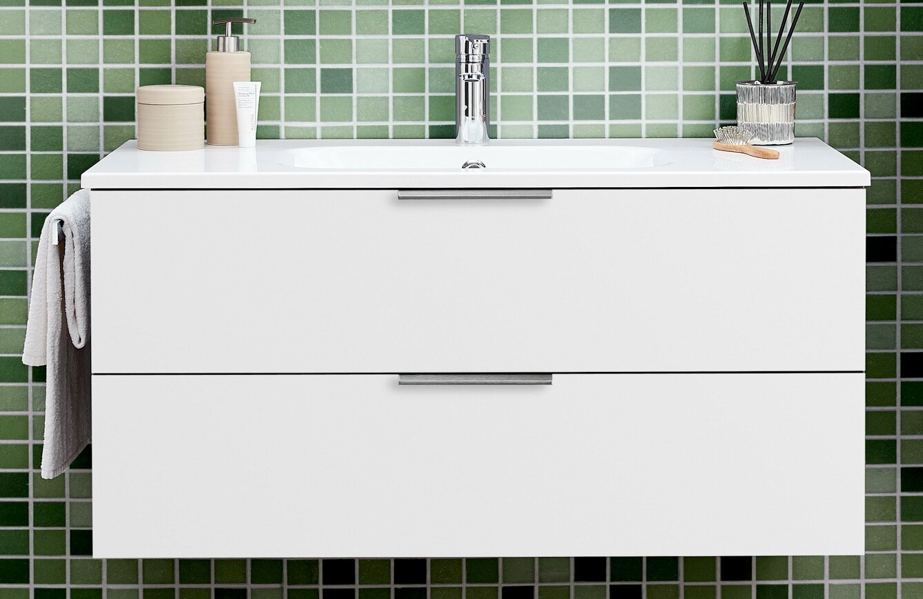 Sadena Waschtisch-Set KÖLN Weißer, wandhängender Waschtisch-Unterschrank mit integriertem Waschbecken und Chromarmatur vor grüner Fliesenwand, Frontansicht auf Augenhöhe.