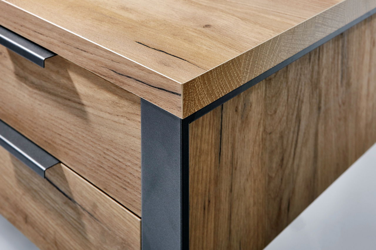 Nahaufnahme eines Schreibtisches aus Holz mit Metallakzenten, perspektivisch von der Ecke aufgenommen.