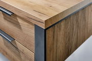 Nahaufnahme eines Schreibtisches aus Holz mit Metallakzenten, perspektivisch von der Ecke aufgenommen.