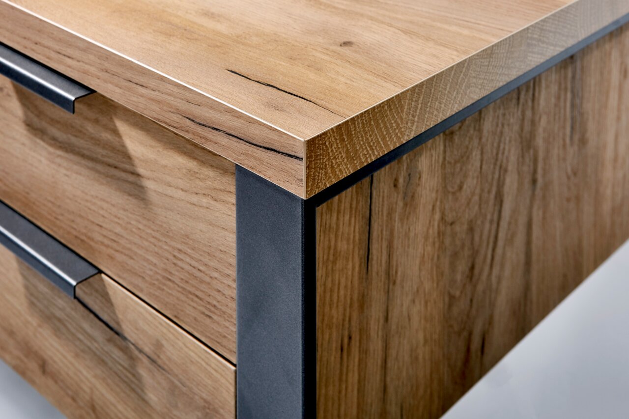 Close-up van een houten bureau met metalen accenten, vanuit de hoek gefotografeerd.