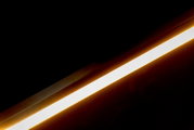 Schuine close-up van een langwerpige LED-lichtbalk met warmwitte gloed tegen een donkere achtergrond