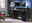 Moderner schwarzer Schreibtisch mit zwei Monitoren, Gaming-Zubehör und einem Gaming-PC, seitliche Perspektive.