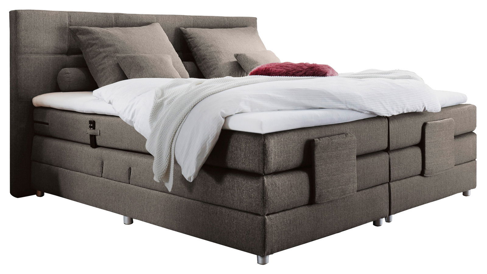 Boxspringbett in seitlicher Perspektive mit grauem Stoffbezug, zwei großen Kissen und einer weißen Decke.