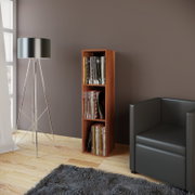 Schmales Holzregal in warmem Nussbaumton mit drei Fächern, gefüllt mit Schallplatten, im Wohnzimmer neben schwarzem Sofa und moderner Stehlampe; Perspektive: leicht seitliche Frontansicht auf Augenhöhe.