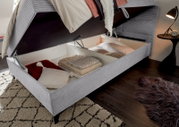Boxbett mit geöffnetem Stauraum, gefüllt mit Kissen und Decken, aus seitlicher Perspektive.