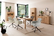 Moderne Esszimmer-Einrichtung mit Holztisch, gepolsterten Drehstühlen und Vitrinen in einem hellen Raum mit großen Fenstern, seitliche Perspektive.