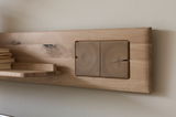 Nahaufnahme eines Wandboards aus Holz mit natürlicher Maserung und integrierten Ablageflächen, seitliche Perspektive.