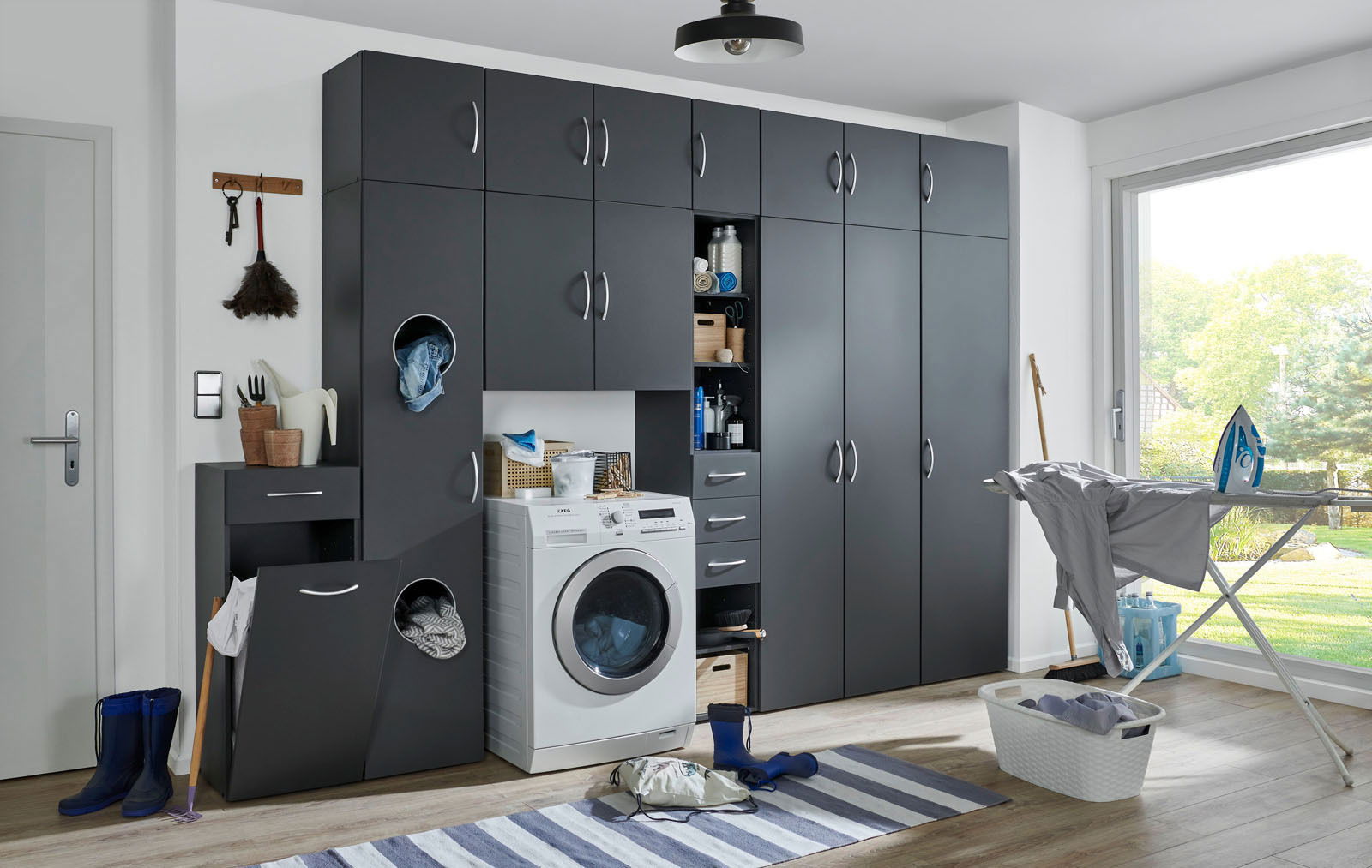 XORA Hängeschrank MULTIRAUMKONZEPT Moderne Waschküche mit grauen Schränken, Waschmaschine und Bügelstation, seitliche Perspektive