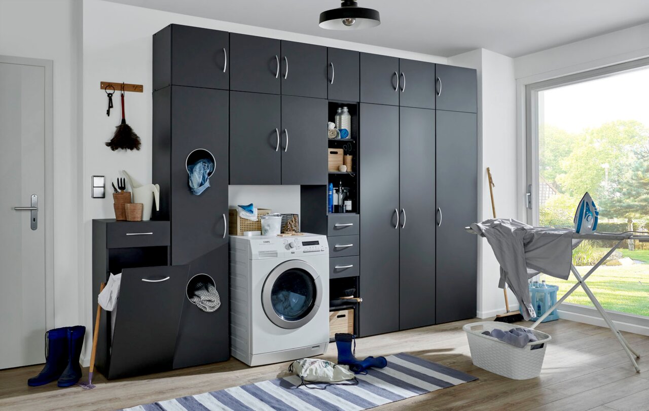 Moderne Waschküche mit grauen Schränken, Waschmaschine und Bügelstation, seitliche Perspektive