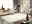 Heller Uni-Teppich in einem modernen Wohnzimmer, fotografiert aus einer leicht erhöhten Perspektive. Der Teppich liegt auf einem glänzenden Fliesenboden, umgeben von stilvollen Möbeln und Dekorationen.