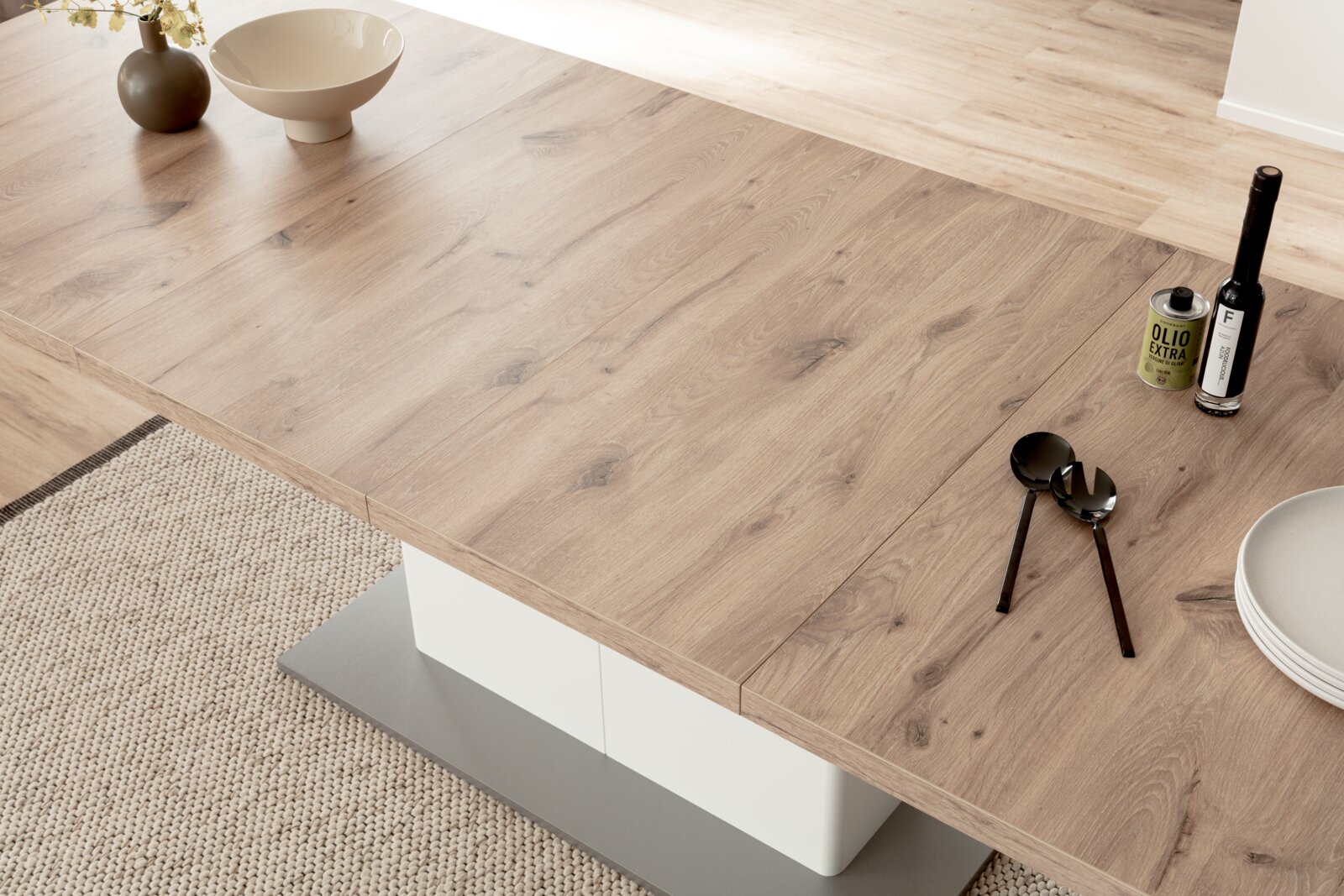 Een moderne houten eettafel in close-up, gefotografeerd van bovenaf, met decoraties zoals een vaas, schalen en bestek.