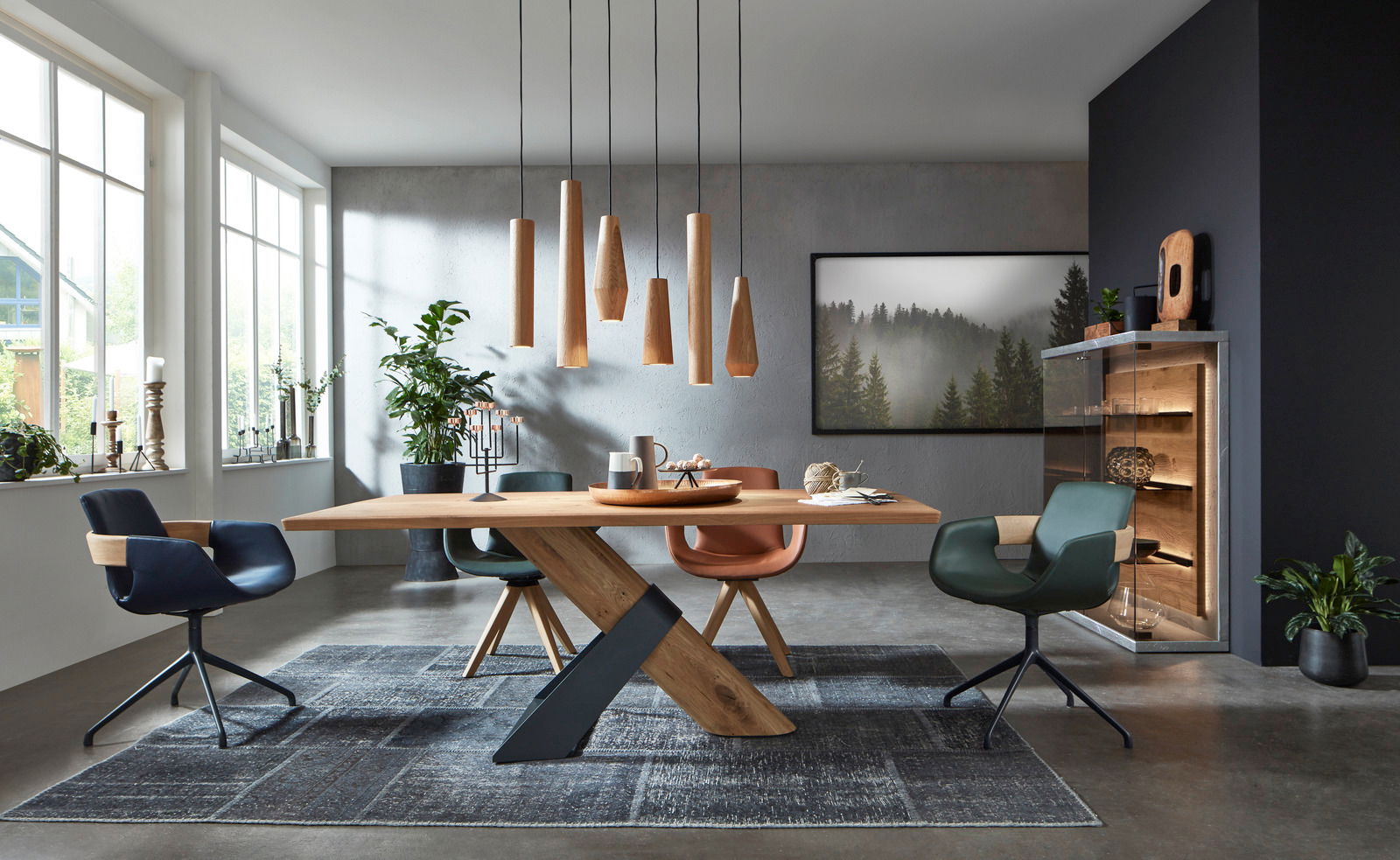 Moderner Essbereich mit stilvollen Armlehnstühlen in verschiedenen Farben um einen Holztisch, aus der Perspektive des Raumes betrachtet.