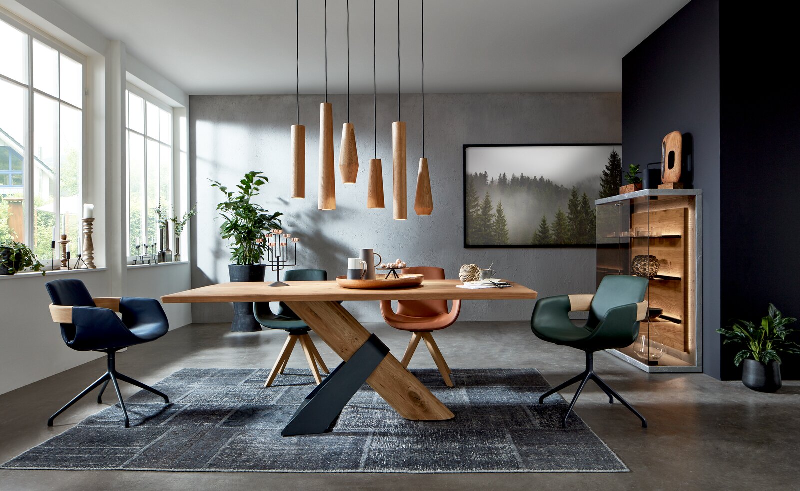 Moderner Essbereich mit stilvollen Armlehnstühlen in verschiedenen Farben um einen Holztisch, aus der Perspektive des Raumes betrachtet.