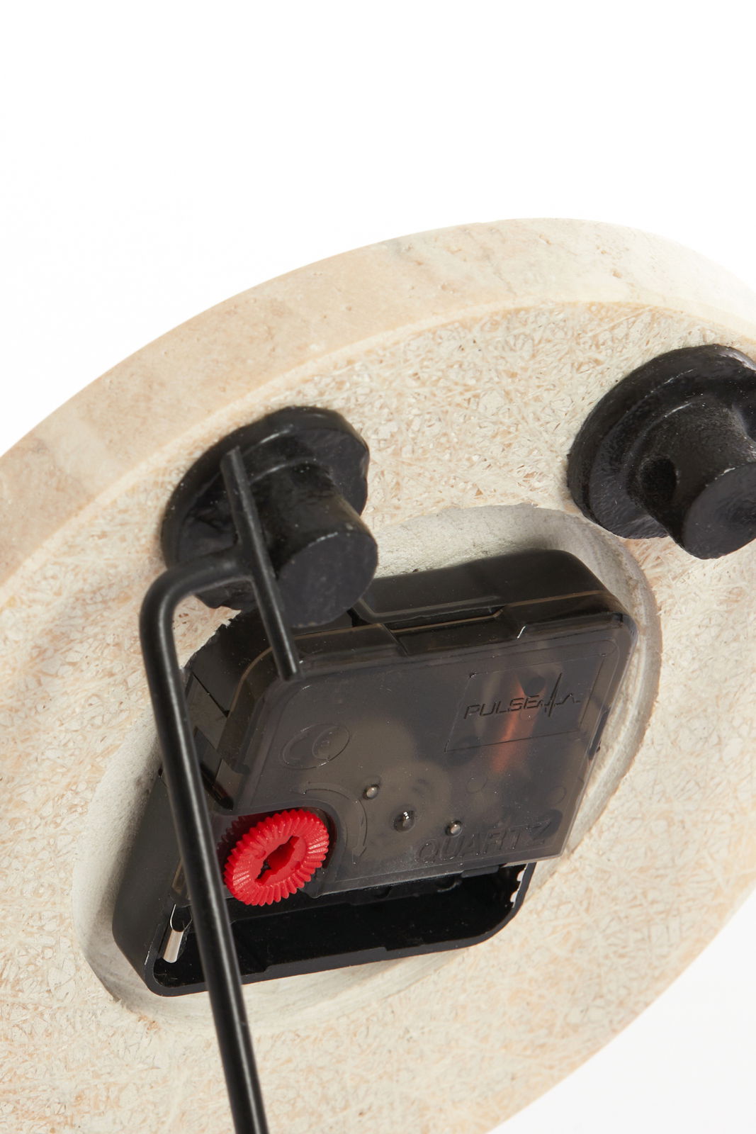 Rückansicht eines Uhrwerks mit sichtbarem Quarzmechanismus und rotem Einstellrad, montiert auf einer runden Holzplatte.