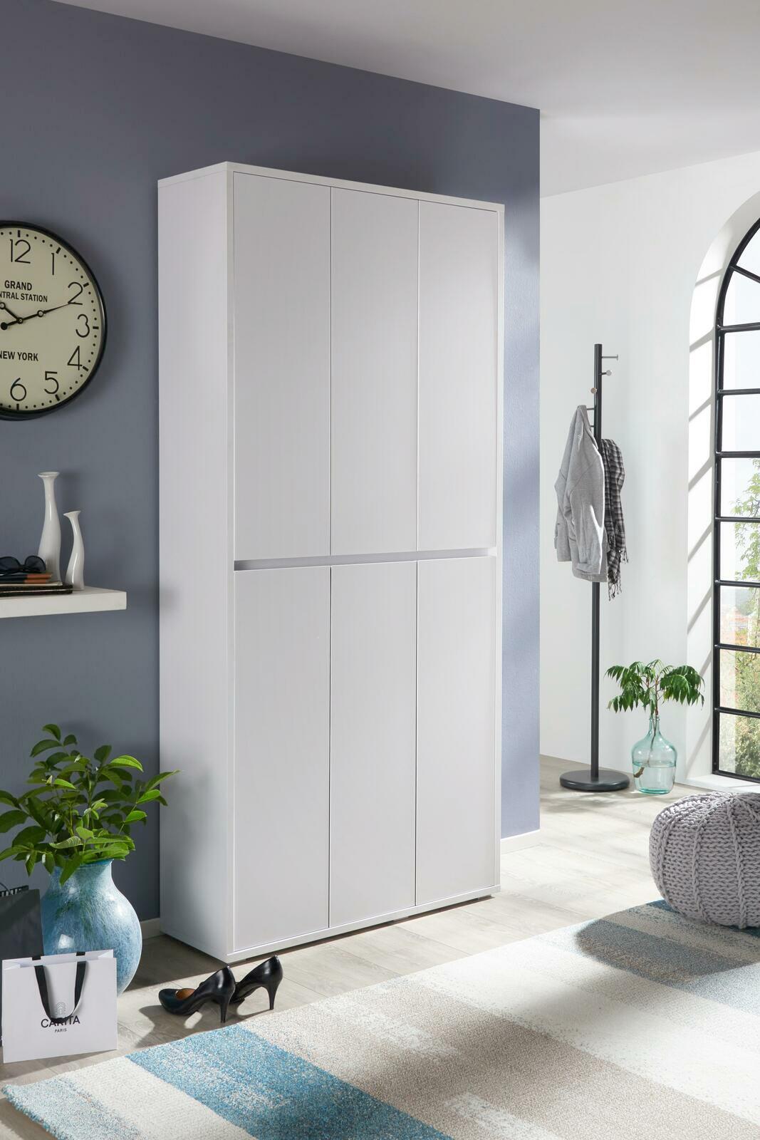 Weißer Schuhschrank in einem modernen Raum, frontal fotografiert, mit dekorativen Elementen wie einer Uhr und Pflanzen.