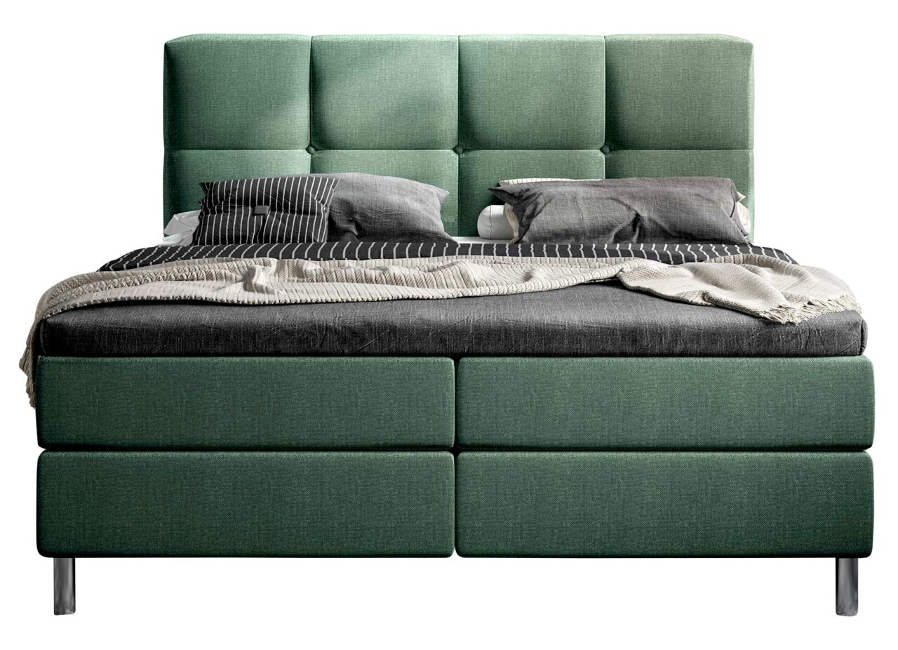 Grünes Boxbett mit gestepptem Kopfteil, frontal fotografiert, mit grauer Bettwäsche und Kissen.