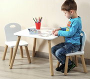 Kindertisch mit zwei weißen Stühlen, ein Kind sitzt und spielt am Tisch, seitliche Perspektive