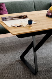 Moderner Esstisch mit Holzplatte und schwarzem Metallgestell, seitliche Perspektive.