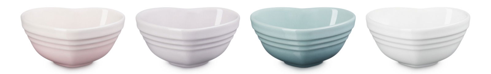 Vier Mini-Herzschälchen in verschiedenen Pastellfarben, von links nach rechts: rosa, lila, blau und weiß, aus einer leicht seitlichen Perspektive fotografiert.