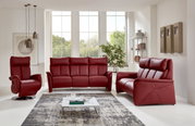 Rotes Ledersofa-Set bestehend aus einem Dreisitzer, einem Zweisitzer und einem Sessel in einem modernen Wohnzimmer mit großen Fenstern, von vorne betrachtet.