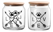 Glasdose mit Holzdeckel, verziert mit schwarzen Pfeilen, Herzen und Pfotenabdruck, aus der Frontalperspektive.