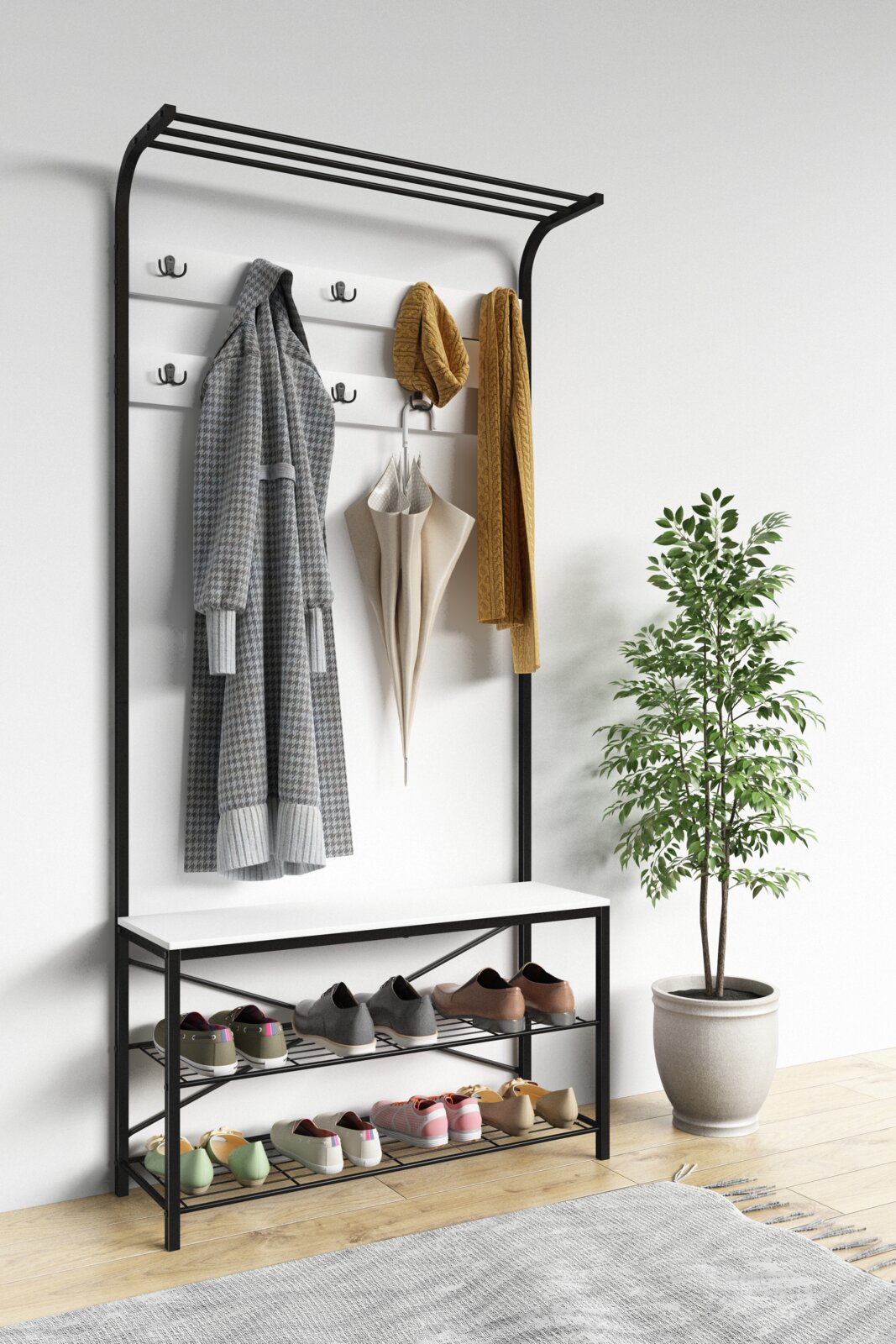 Moderner Garderobenständer aus schwarzem Metall mit weißer Rückwand, Hutablage, mehreren Haken, Sitzbank und zweistöckigem Schuhregal, frontal in leichter Schrägansicht von links fotografiert daran hängen Mantel, Schal und Regenschirm in einem hellen Flu