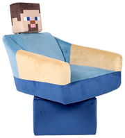Minecraft-inspirierter Plüsch-Sessel in Blau und Beige mit pixeligem Kopf, schräg von vorne links fotografiert