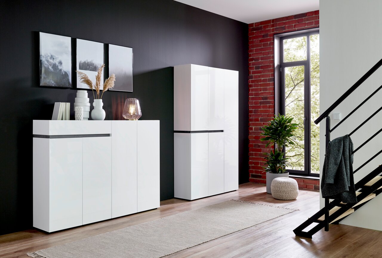 Moderner weißer Schuhschrank und Sideboard in einem stilvollen Wohnzimmer mit schwarzer Wand und großen Fenstern, seitliche Perspektive.