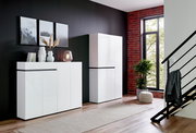 Moderner weißer Schuhschrank und Sideboard in einem stilvollen Wohnzimmer mit schwarzer Wand und großen Fenstern, seitliche Perspektive.