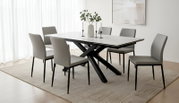 Moderne rechthoekige eettafel met licht marmerlook blad en zwart gekruist onderstel, omringd door zes grijze stoelen, gezien schuin van voren in een lichte eetkamer.
